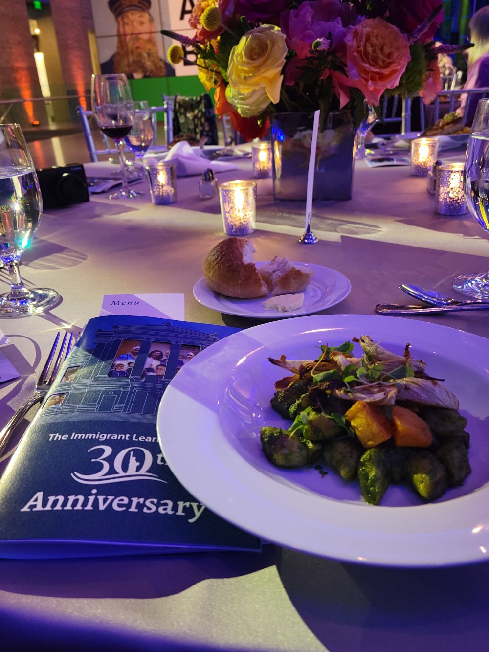 Photo of The Immigrant Learning Center's 30th Anniversary program book with the dinner course salad.